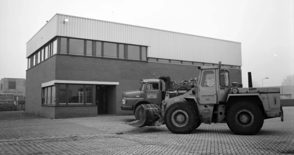 Zwart-witfoto van het oude REKO-pand met shovel en vrachtwagen